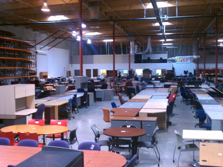 Bulk corporate office furniture and modular workstation layouts stored in a clearance liquidation warehouse yard