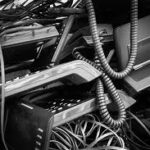 A pile of discarded corporate office landline desk phones, tangled coiled receiver cords, and telecom e-waste cables ready for recycling.