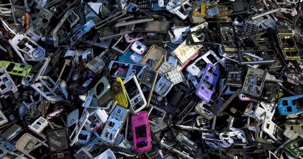 A massive pile of decommissioned feature phone bodies, mobile phone chassis, and plastic electronic casings collected for bulk e-waste scrap recycling.