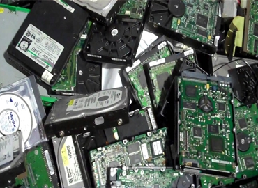 Find old e-waste scrap buyers near you in Bangalore 2 corporate hard drives, logic boards, and green printed circuit board PCB scrap awaiting secure data destruction and metal recycling
